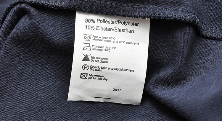 Tekst o toksycznych substancjach w odzieży syntetycznej. Na zdjęciu: Etykietka biała na niebieskim materiale - HelloZdrowie