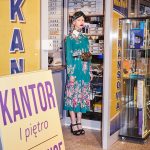 Zuzanna Bartoszek w sesji dla Reserved, fot. Zuza Krajewska. Modelka ubrana w kwiecistą sukienkę i chustę stoi w wejściu do kantoru