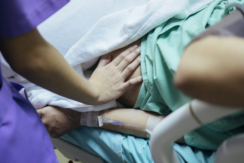 Położna trzyma rękę na brzuchu ciężarnej kobiety