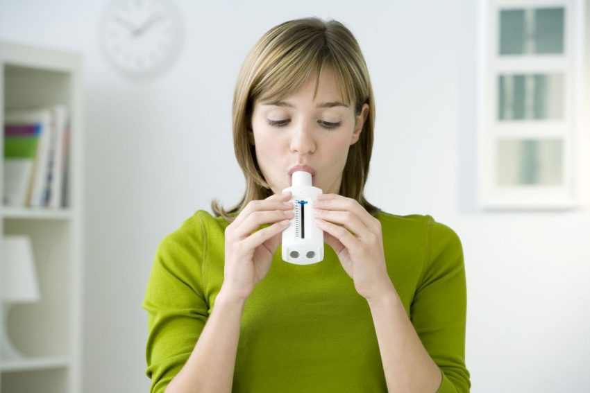 spirometria - kobieta wpuszcza powietrze do urządzenia