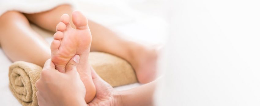Fizjoterapeuta wykonuje kobiecie masaż śródstopia
