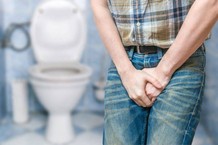 mężczyzna stoi w toalecie i trzyma się za okolice krocza