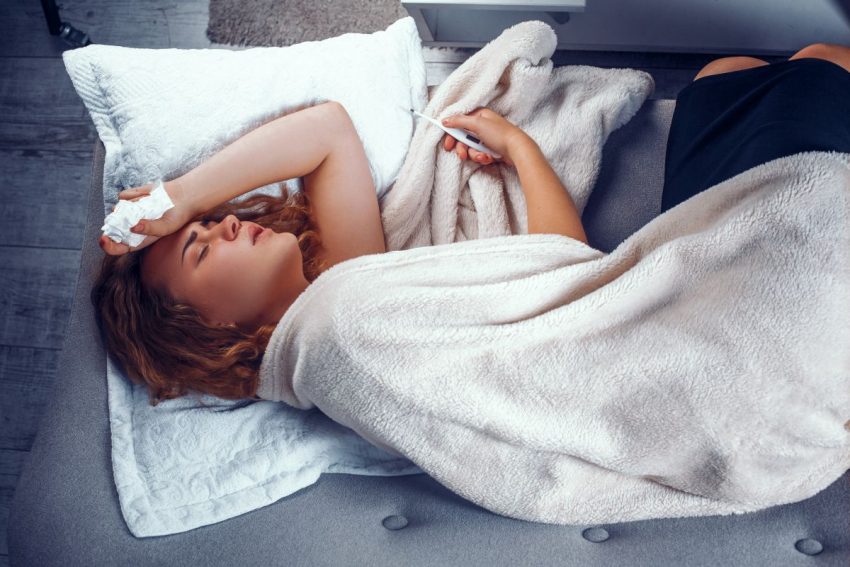Kobieta z chusteczką w ręce leży nakryta kocem