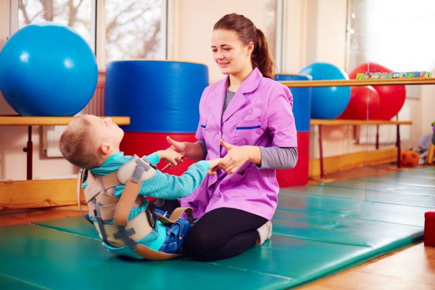rehabilitantka ćwiczy na macie z małym chłopcem