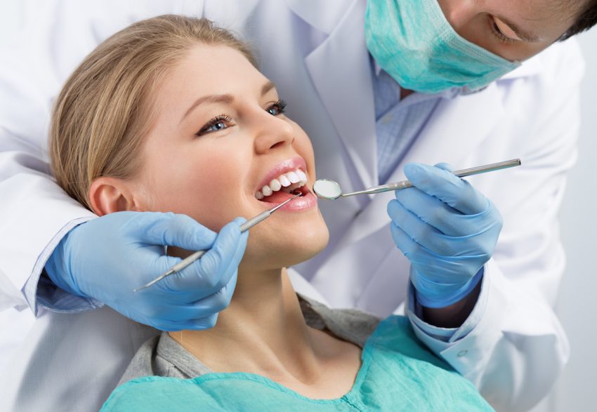 Kobieta cierpiąca na zapalenie dziąseł podczas wizyty u dentysty.