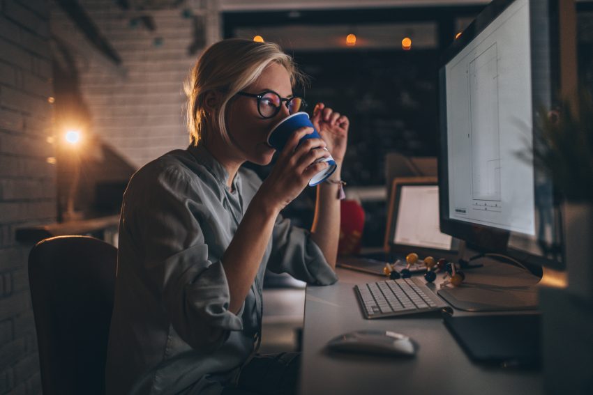 Kobieta pije kawę przed monitorem