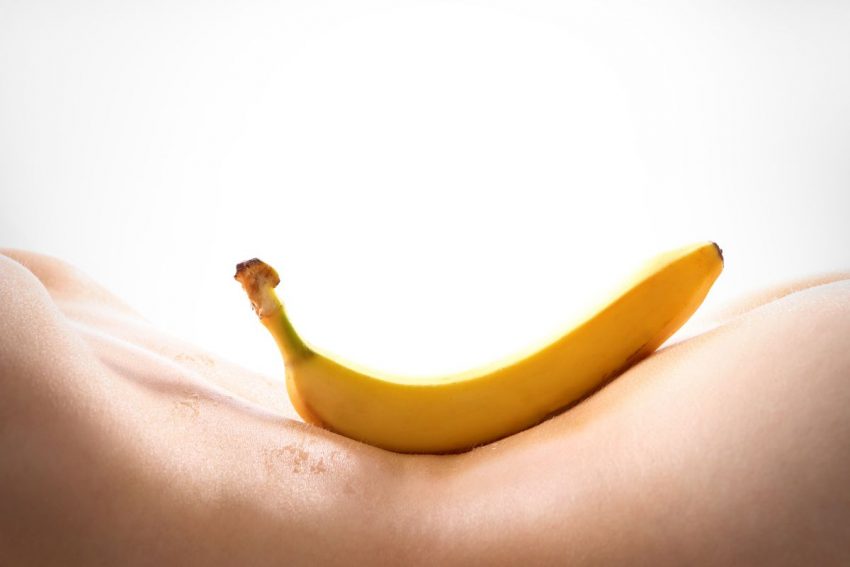 Na ciele kobiety leży banan