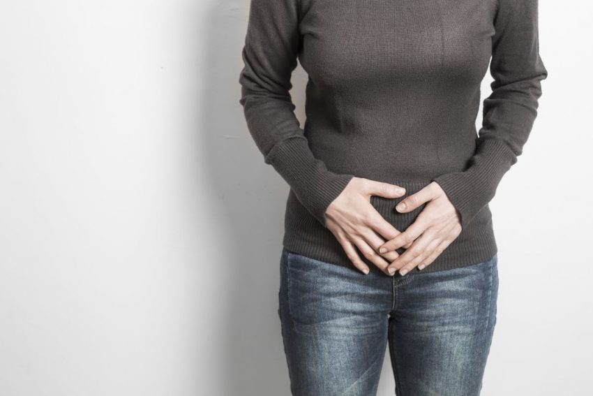 Kobieta trzymająca się za brzuch z powodu zapalenia cewki moczowej