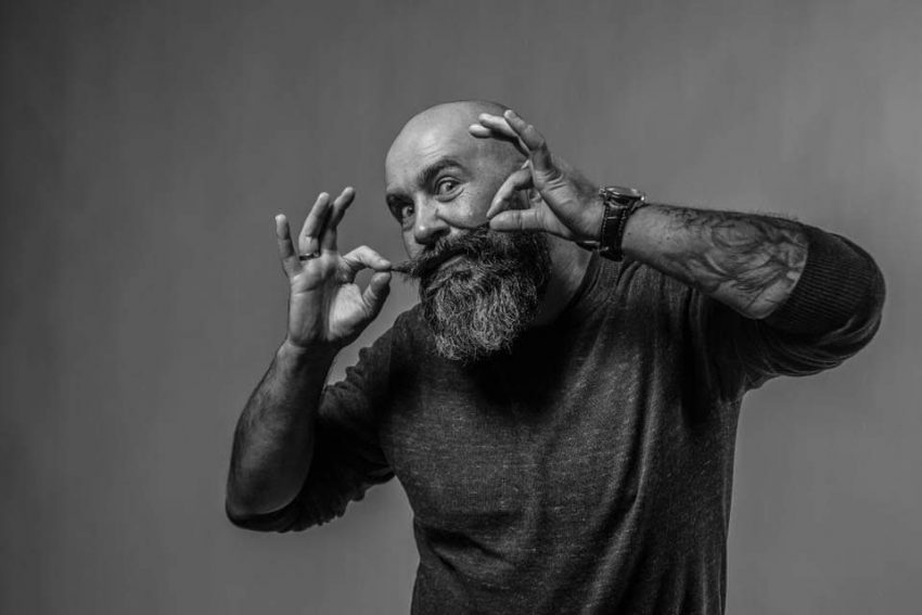 Tekst o kampanii samobadania jąder w Movember. Na zdjęciu: Mężczyzna z brodą gestykulujący rękoma - HelloZdrowie