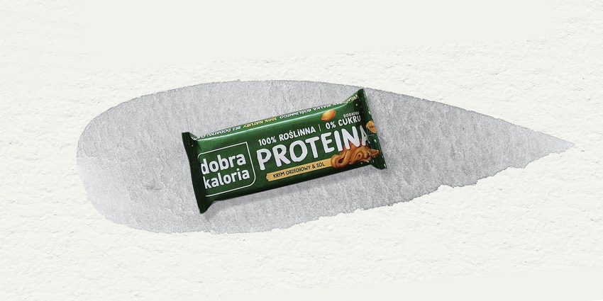 Tekst o batonach proteinowych, ich składzie i korzyściach. Na zdjęciu: Zielone opakowanie z białym tekstem - HelloZdrowie