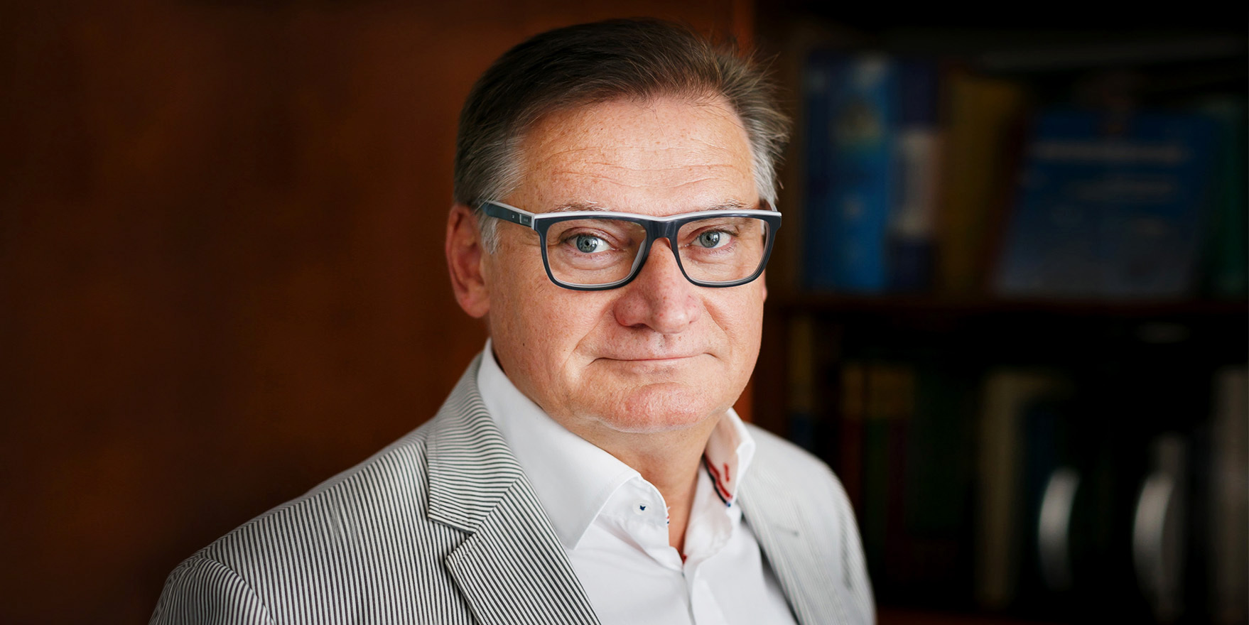 Tekst o zapobieganiu COVID-19 i organizacji życia społecznego. Na zdjęciu: Mężczyzna w okularach i w paskowanej marynarce - HelloZdrowie