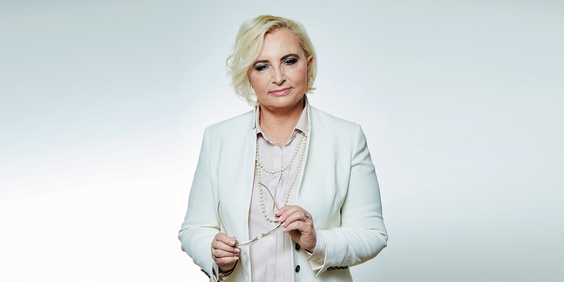 Tekst o chorobach psychosomatycznych wynikających ze stresu. Na zdjęciu: Kobieta w białej marynarce - HelloZdrowie