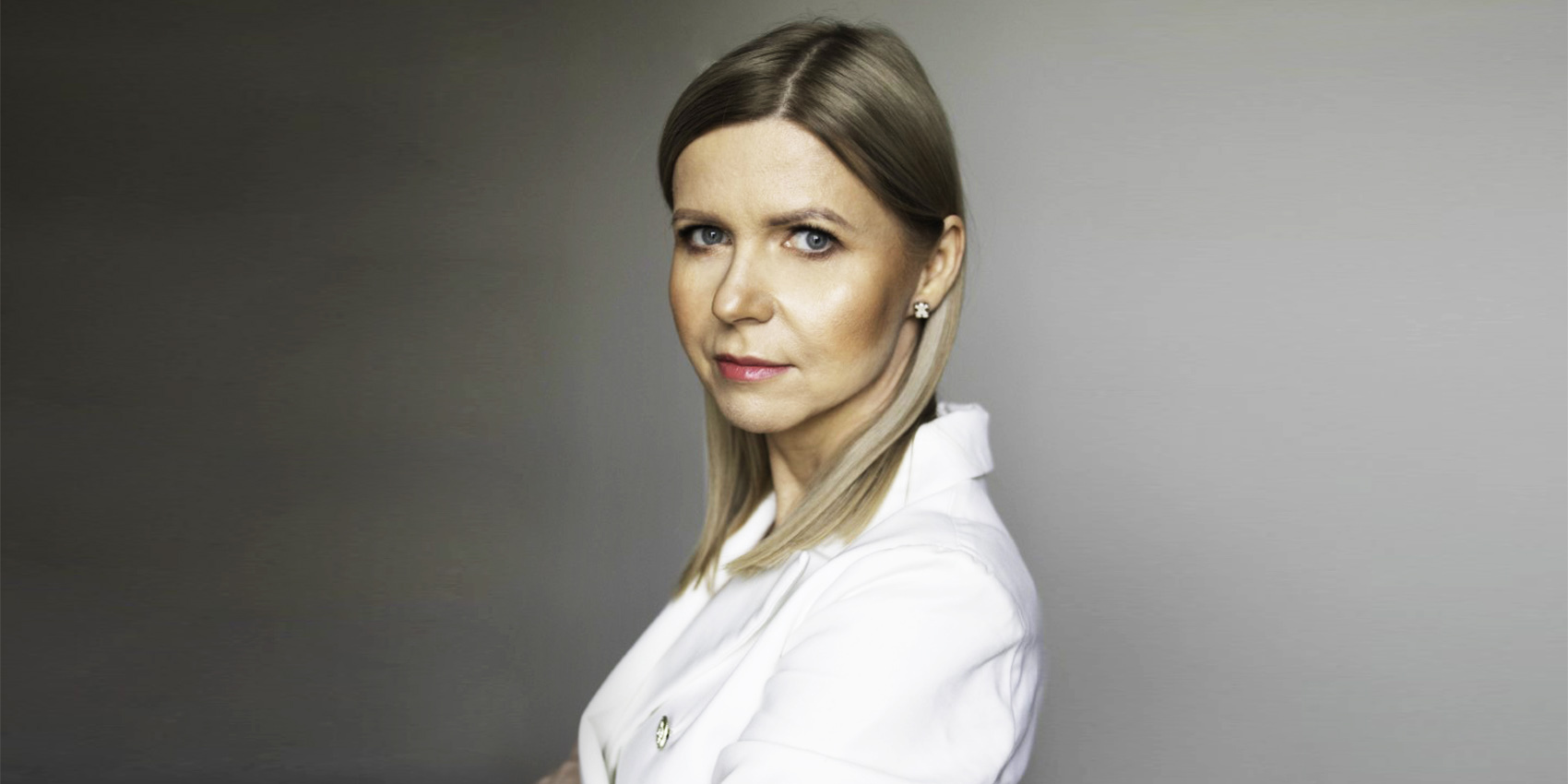 Tekst o mobbingu w pracy i jego objawach. Na zdjęciu: Kobieta w białej marynarce - HelloZdrowie