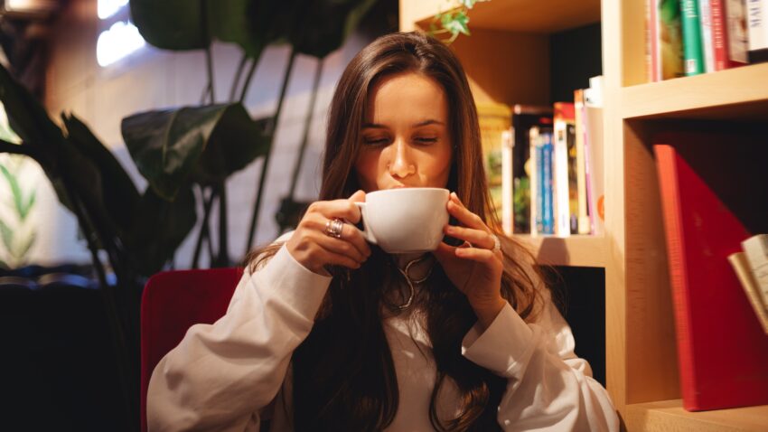 na zdjęciu: kobieta pije coś ciepłego z dużej filiżanki; tekst o tym, jak pokonać zgagę - Hello Zdrowie