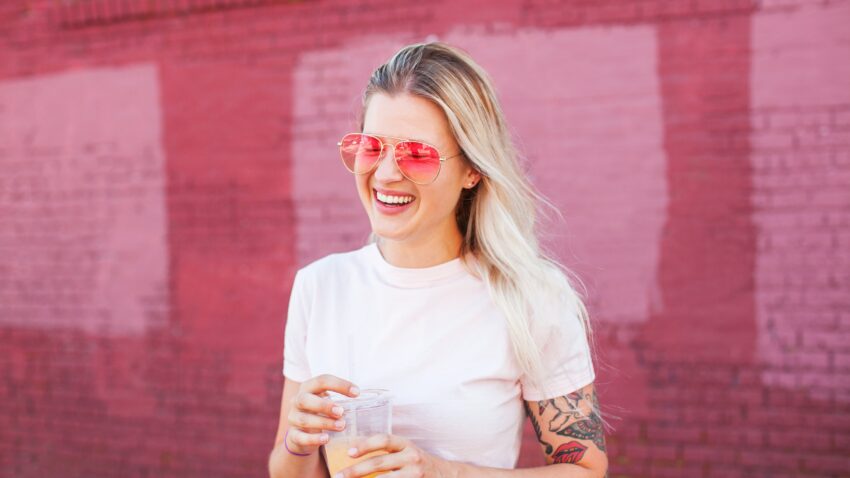 Kobieta w różowych okularach uśmiecha się