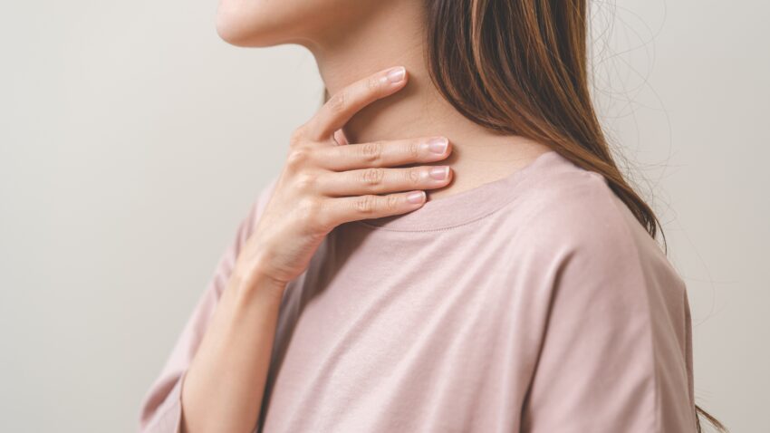 Kobieta przykłada dłoń do szyi