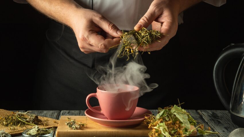 mężczyzna wkłada zioła do parującej filiżanki - Hello Zdrowie