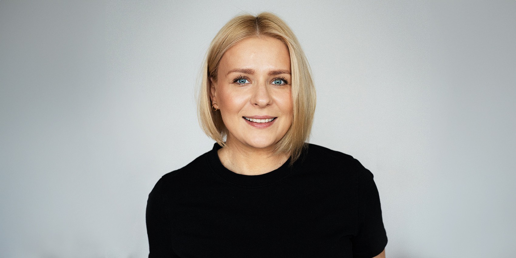 Aneta Zając o tym, jak w środowisku aktorskim traktowane są aktorki z wyższą masą ciała - na zdjęciu aktorka w czarnej koszulce z krótkim rękawem, blond włosy, delikatny uśmiech Hello Zdrowie