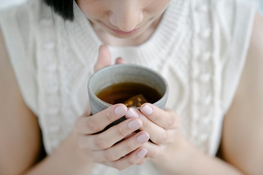 Kobieta trzyma w rękach kubek z herbatą