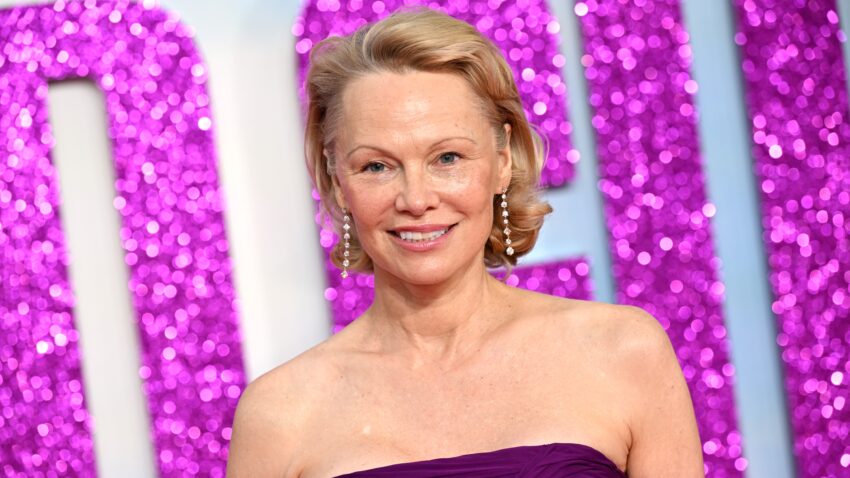Pamela Anderson na tle różowej brokatowej ścianki