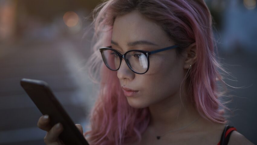 kobieta z różowymi włosami patrzy w ekran telefonu - Hello Zdrowie