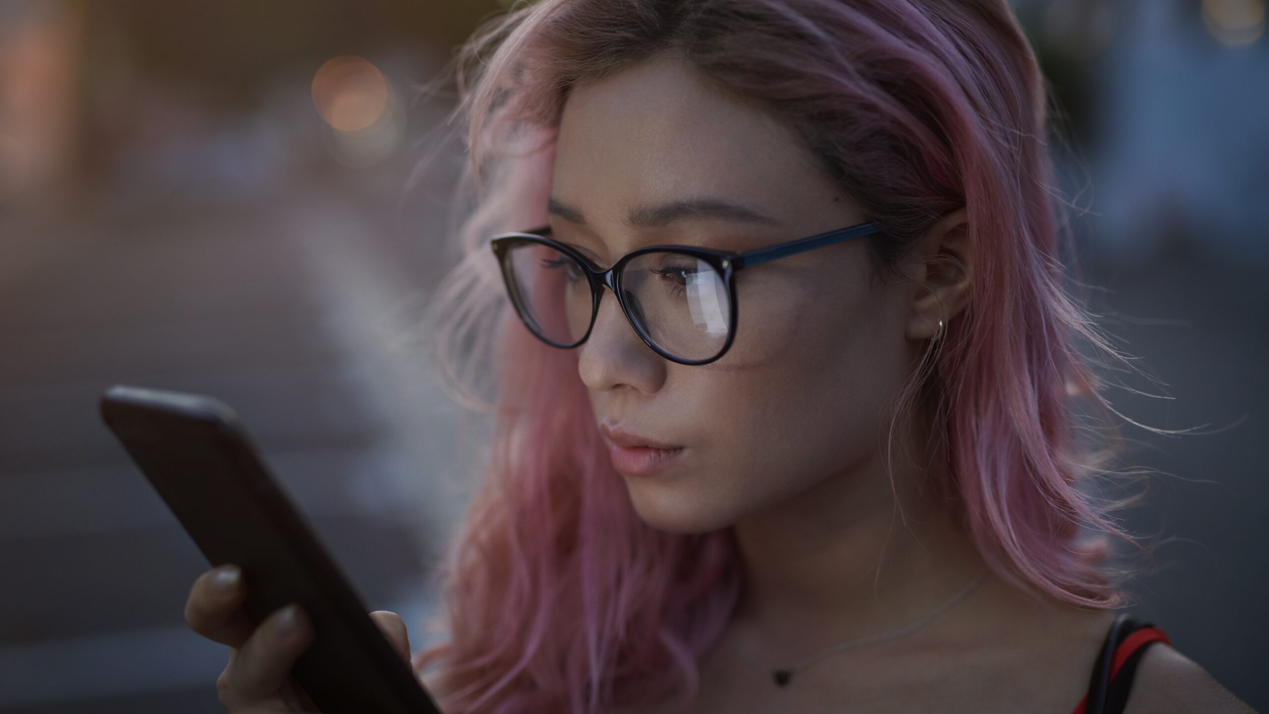 kobieta z różowymi włosami patrzy w ekran telefonu - Hello Zdrowie