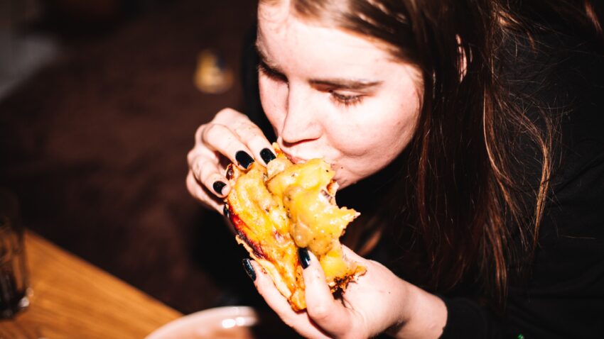 kobieta objada się hamburgerem - Hello Zdrowie