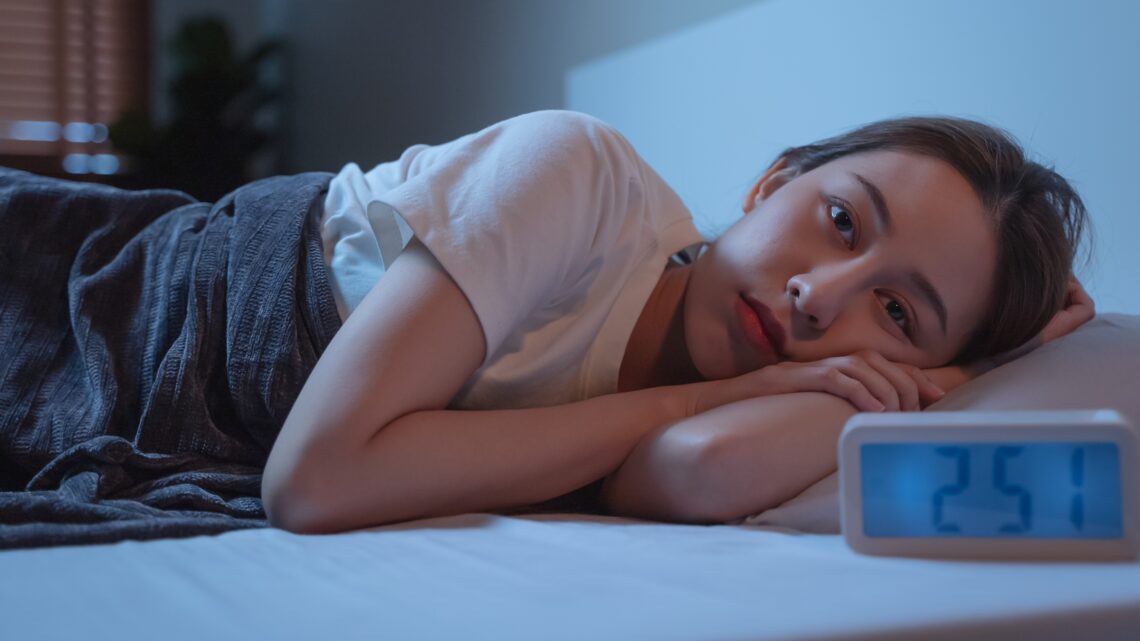 na zdjęciu: kobieta przebudzona w środku nocy leży w łóżku, tekst o tym, jaki wpływ na sen ma mikrobiom - Hello Zdrowie