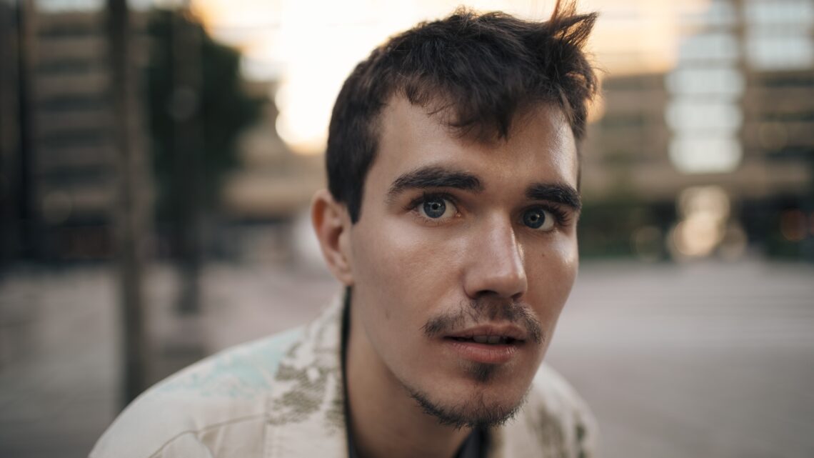 młody mężczyzna z generacji Z patrzy w obiektyw kamery - Hello Zdrowie