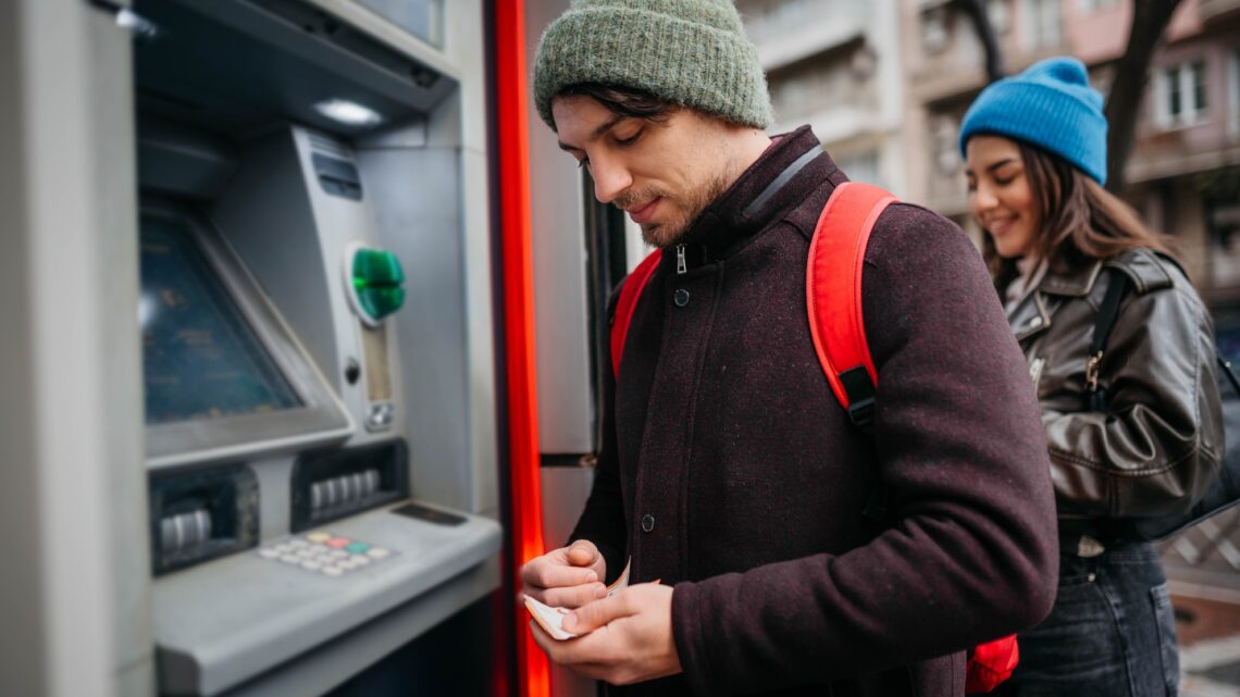 na zdjęciu: para przy bankomacie, tekst o związkach, w których nie ma wspólnych pieniędzy - Hello Zdrowie