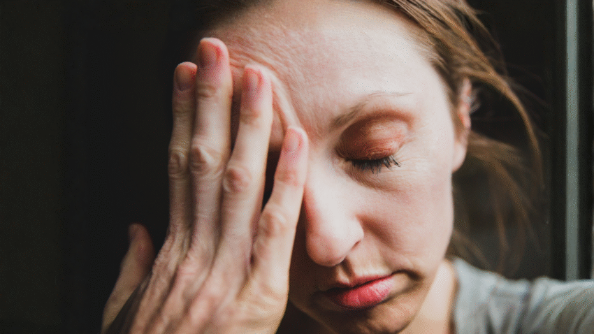 zmęczona kobieta opiera czoło na dłoni, tekst dotyczy objawów tężyczki - Hello Zdrowie