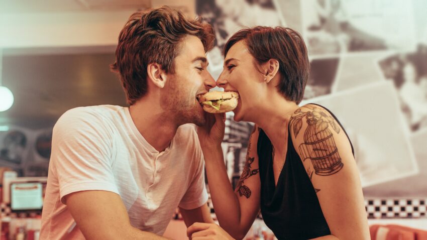 na zdjęciu: para je na spółkę hamburgera; tekst o tym, że małżeństwo pomaga utrzymać niższą wagę - Hello Zdrowie