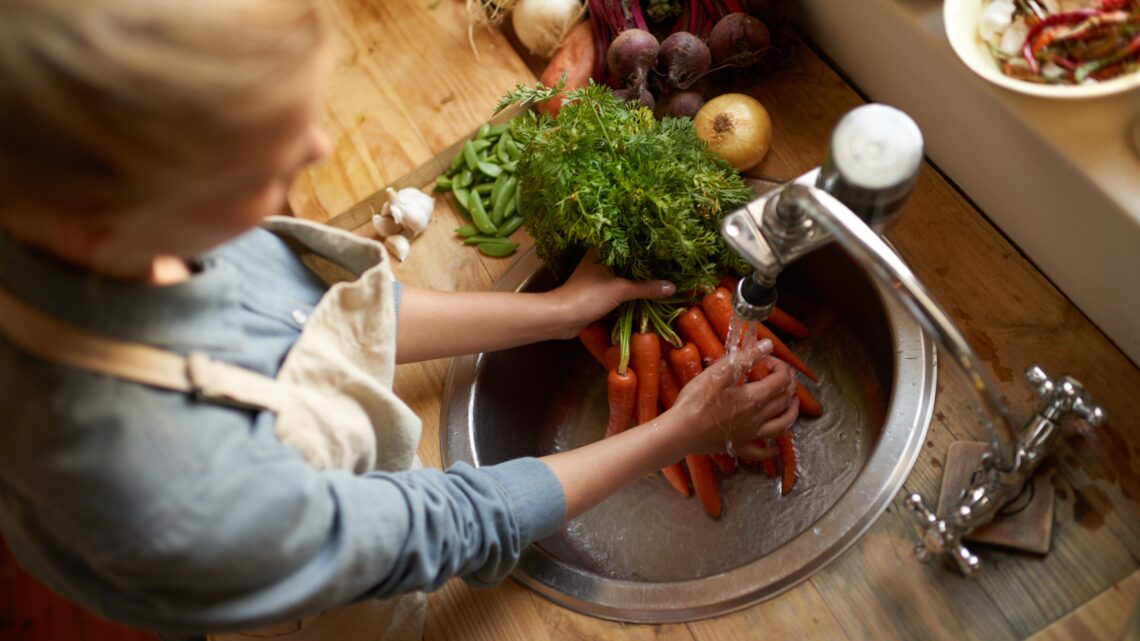 Kobieta myje warzywa pod bieżącą wodą