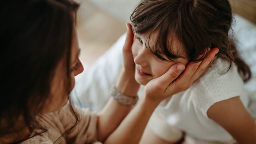 mama otula dłońmi twarz córki - Hello Zdrowie