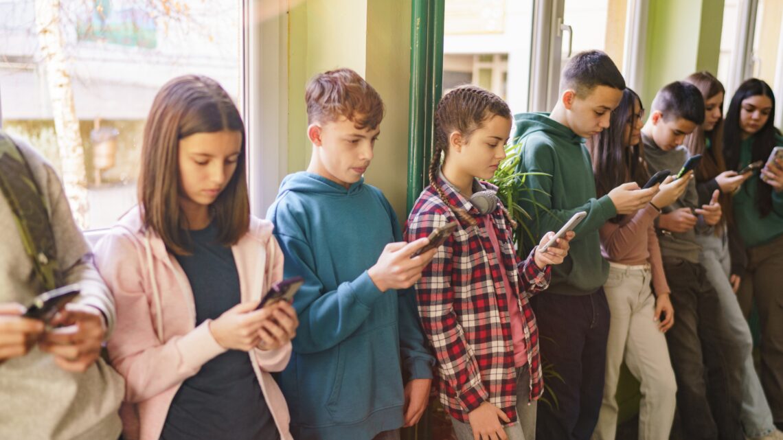 uczniowie w czasie przerwy wpatrzeni w telefony komórkowe - Hello Zdrowie