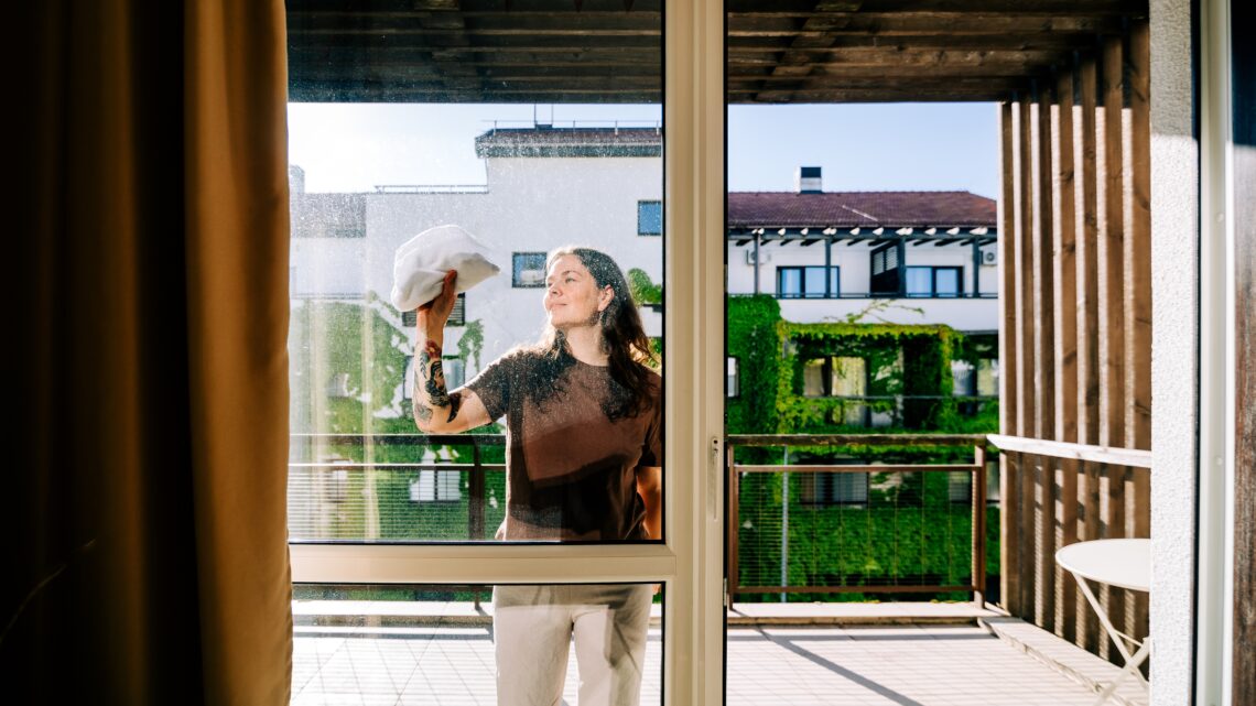 kobieta myje okno na balkonie - Hello Zdrowie